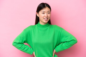 Young Chinese woman isolated on pink background posing with arms at hip and smiling