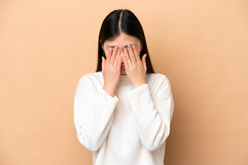 Young Chinese woman isolated on beige background with tired and sick expression