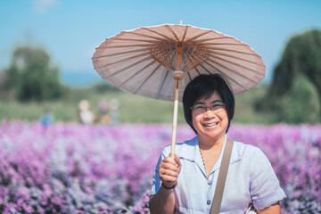 Old mature smile traveler asian thai woman relax on flower field in garden at Chiang Mai Thailand Happy elder enjoying travel holiday vacation moment concept © Peera