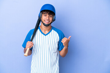 Baseball caucasian man player with helmet and bat isolated on blue background pointing to the side to present a product