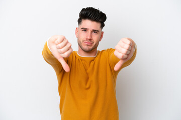 Young caucasian man isolated on white background showing thumb down with two hands
