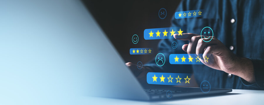 Person interacting with digital customer feedback and star rating icons on a laptop screen. Concept of online reviews and service satisfaction.