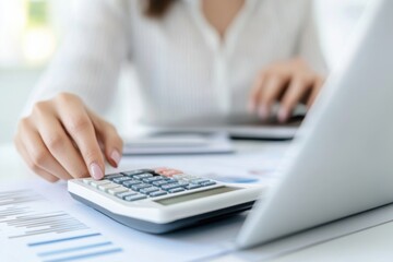 Financial Calculations: Woman using calculator with laptop and charts for accounting tasks