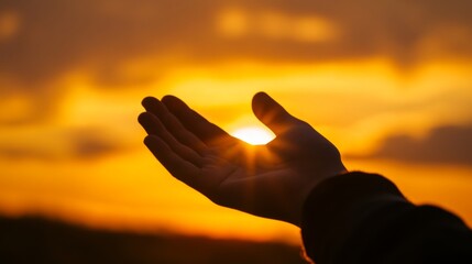 Silhouette of hand touching the setting sun against orange sky