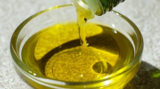 Unrefined extra virgin olive oil pouring out of bottle slow motion.