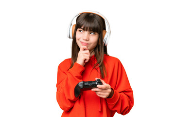 Little caucasian girl playing with a video game controller over isolated background and looking up © luismolinero