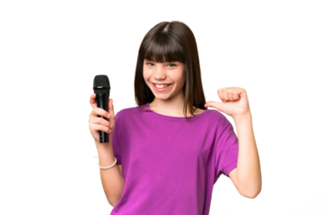 Little singer girl picking up a microphone over isolated background proud and self-satisfied