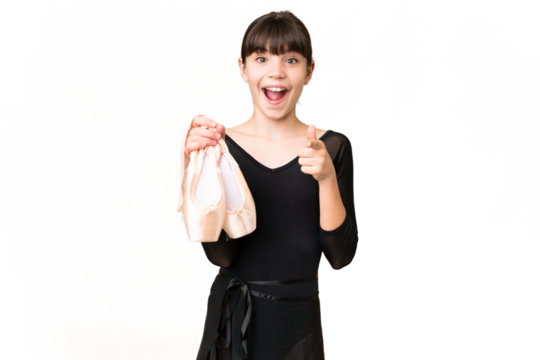 Little caucasian girl practicing ballet over isolated background surprised and pointing front