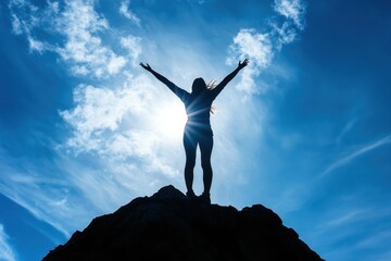A woman standing on top of a mountain, arms raised towards the blue sky. Her silhouette exudes strength,and freedom, her flowing hair blending into the bright sky. Cocept for travel and woman power.