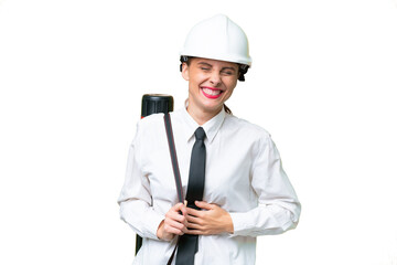 Young architect woman with helmet and holding blueprints over isolated background smiling a lot