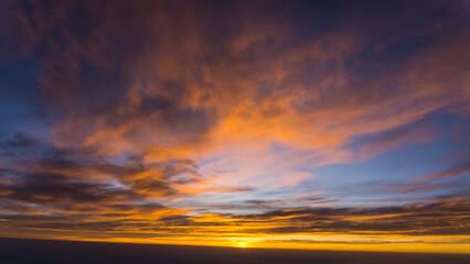 Breathtaking view to the clouds during sunset on Tenerife islands shows dramatic sky with rich orange colours when travelling during summer vacation in this volcanic island.