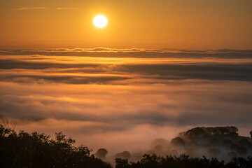 Nascer do sol sobre nevoeiro numa serra
