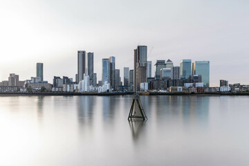 Canary Wharf shot from the Greenwich peninsula at slack tide with an ethereal sky, creating a...
