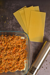 Top view. Bolognese sauce in a glass form. Lasagne pasta sheets, pepper mill. Black background....
