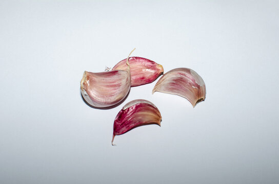 Red garlic cloves on a white background.