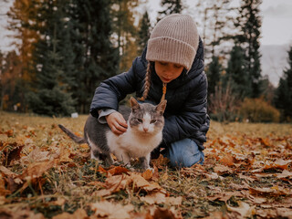 Autumn walk in the forest. Little girl with cat in the forest in autumn