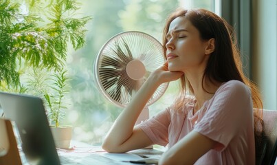 Naklejka premium Woman enjoying cooling fan near a window.