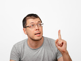 A brilliant idea comes to mind. Smart unshaven man in glasses raising index finger up isolated on white background.