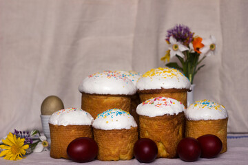 Easter bread with icing and colourful sprinkles on a table with Easter eggs and spring flowers. Place for text