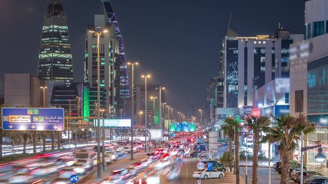 Cityscape aerial night timelapse of Riyadh, Saudi Arabia, featuring illuminated towers, skyscrapers, King Fahd Road and busy traffic. Palms and streetlights line the main highway through the city.