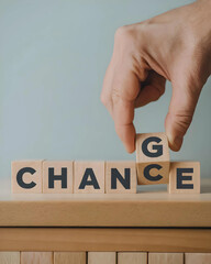 A hand reaches down to rotate a wooden block with the letter G, changing the word on the blocks from Change to Chance.
