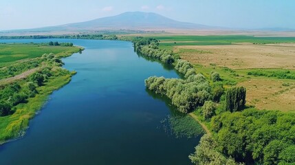 Scenic river winds through lush farmland, mountain backdrop