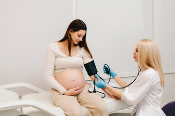 High pressure problem during pregnancy. Gynecologist measures blood pressure for pregnant patient...