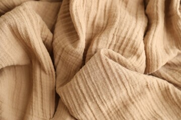 Texture of crumpled linen fabric under natural light in peach fuzz color