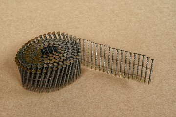 A coil of nail gun framing nail isolated on brown