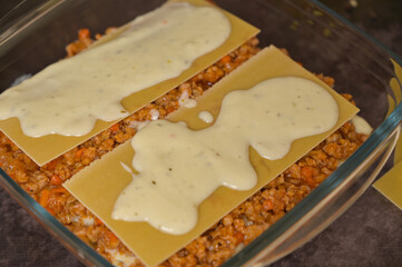 Close-up. Homemade lasagna cooking preparation. Lasagne pasta sheets, Bolognese and béchamel...