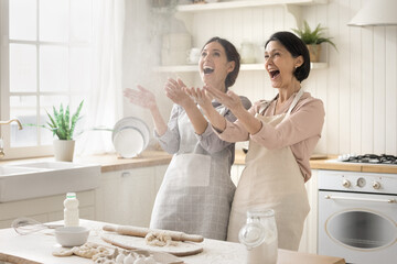 Behaving like a naughty child. Overjoyed young woman adult daughter enjoy home cooking together...