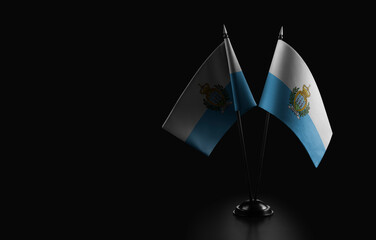 Small national flags of the San Marino on a black background