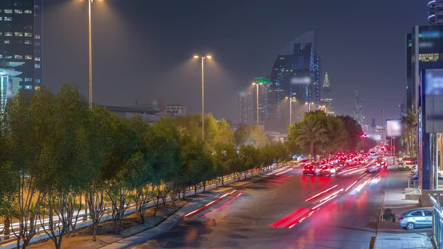 Aerial night timelapse of Riyadh, Saudi Arabia, featuring illuminated towers, skyscrapers, King Fahd Road and busy traffic. Palms and streetlights line the main highway through the foggy city.