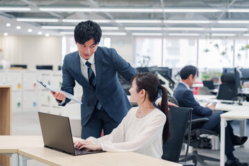 オフィスのデスクで打ち合わせをする男女のビジネスパーソン