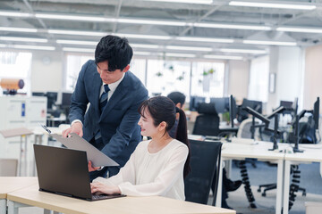 オフィスのデスクで打ち合わせをする男女のビジネスパーソン