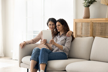 Sharing memories with beloved parent. Friendly family older age mom grown up daughter relax on...