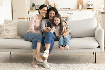Digital fun. 3 female generations senior grandma grownup mom small child girl relax on couch...