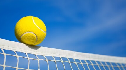 Yellow colored summer games ball against blue sky, beach volleyball or tennis net background for sport events, with ample copy space for branding, promotion, or event advertisements