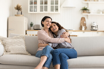 Obraz premium You are always a child in parents house. Sweet moment happy older age mum meet grown up daughter at cozy home cuddle with beloved adult kid on soft couch laugh talk enjoy close emotional connection
