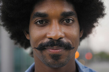 Close-up portrait of smiling young African American man with afro hair and funny mustache