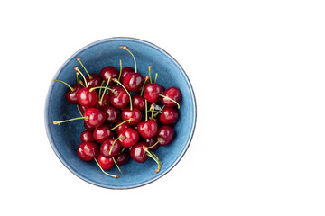 Fresh cherries in a blue ceramic bowl on white background
