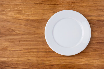 Empty white plate on a wooden table
