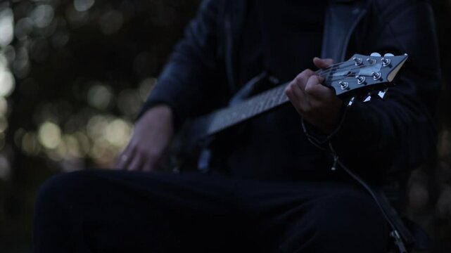 Male musician playing electric guitar outdoors with amplifier in park in autumn