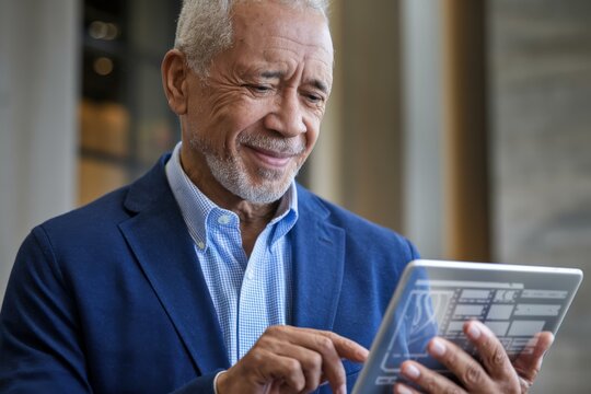 Smiling Older African American Man Blue Blazer Using Tablet Modern Indoor Setting - Tech-Savvy Senior Engaging Digital Technology Active Aging Senior Marketing