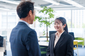 Fototapeta premium 笑顔で上司と話をする若いビジネスウーマン