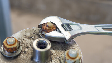 Adjustable wrench used to loosen a rusty bolt on a metal surface.