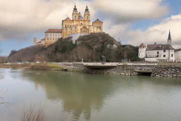Obraz premium Melk, Austria - February 24, 2023: View of Melk Abbey with Collegiate Church towers, mirror reflection in water. It was founded in 11th century, today's baroque abbey was built in 18th century