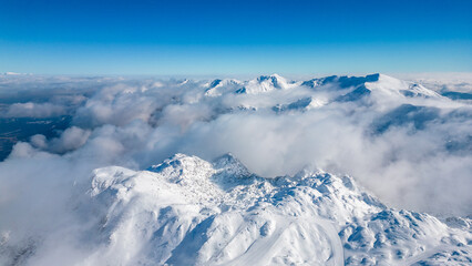 Obraz premium Aerial view of Vogel Ski Resort in Slovenia during winter with blanket of snow covers the slopes and ski lifts in the alpine landscape. Features the striking peaks of Orlove and Pick Sija