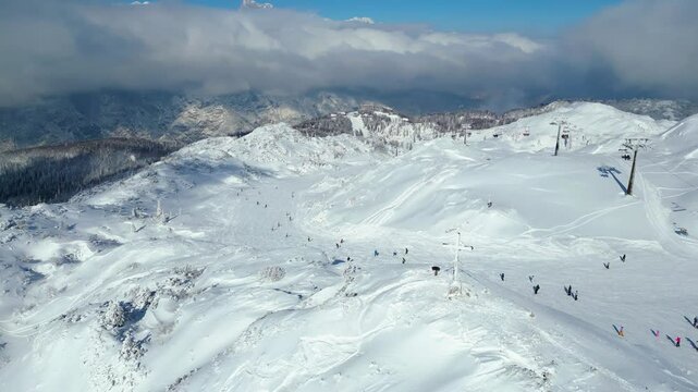 Aerial view of Vogel Ski Resort in Slovenia during winter with blanket of snow covers the slopes and ski lifts in the alpine landscape.  Features the striking peaks of Orlove and Pick Sija
