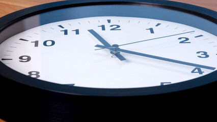 Close-Up of a Black Wall Clock on Wooden Surface.